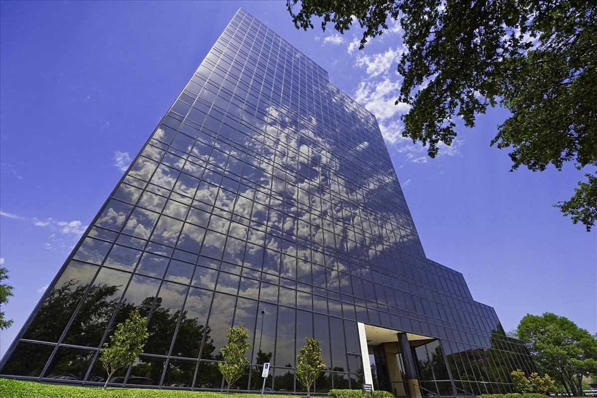 Exterior view of the glass-facade 101 E. Park Boulevard, Suite 600 building reflecting the sky.