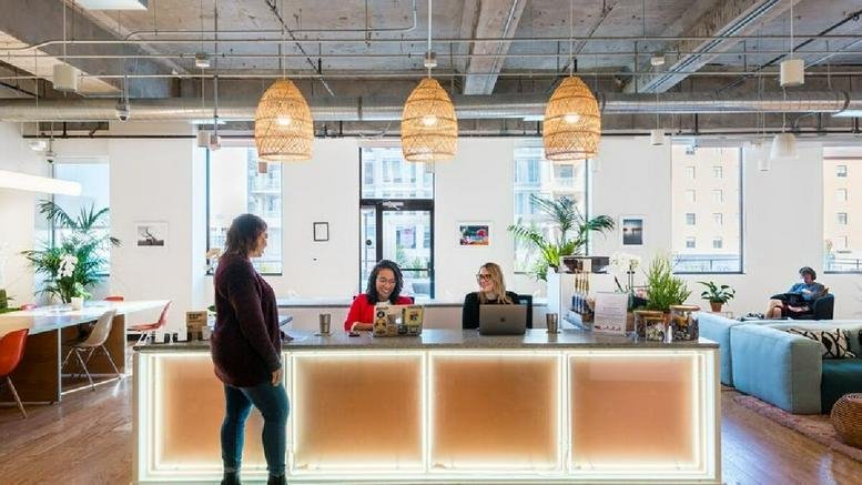 Bright reception desk with three woven pendant lights and a warm, backlit wood-paneled front.