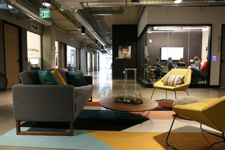 Spacious lounge area featuring a grey sofa, yellow armchairs, and a colourful geometric rug.