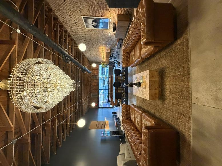 Spacious communal lounge at FreeForm House featuring leather sofas and a large crystal chandelier.