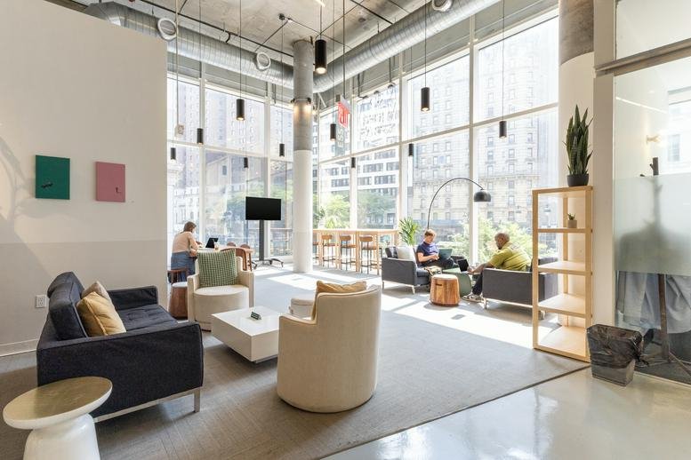 Spacious sun-lit lounge area at 106 West 32nd Street with sofas, armchairs, and floor-to-ceiling city views.