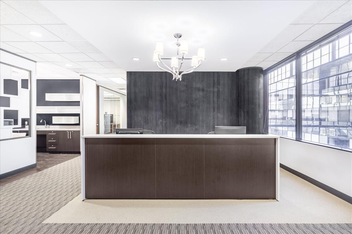 Reception area at 10777 Westheimer, Suite 1100 with a dark wood desk and designer chandelier.