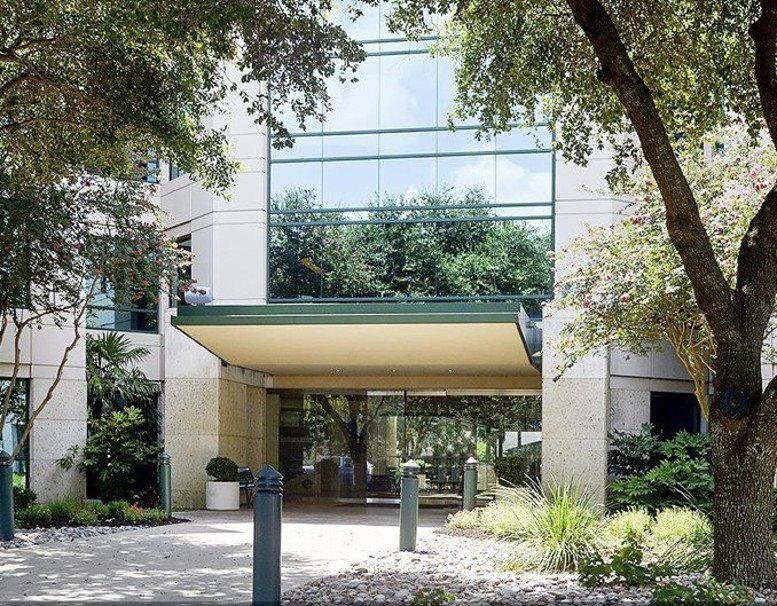 Entrance to the 108 Wild Basin Road building featuring a glass facade and natural greenery.