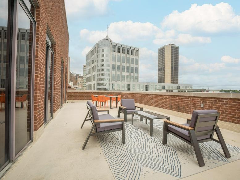 Outdoor rooftop terrace with modern patio furniture and city skyline views.