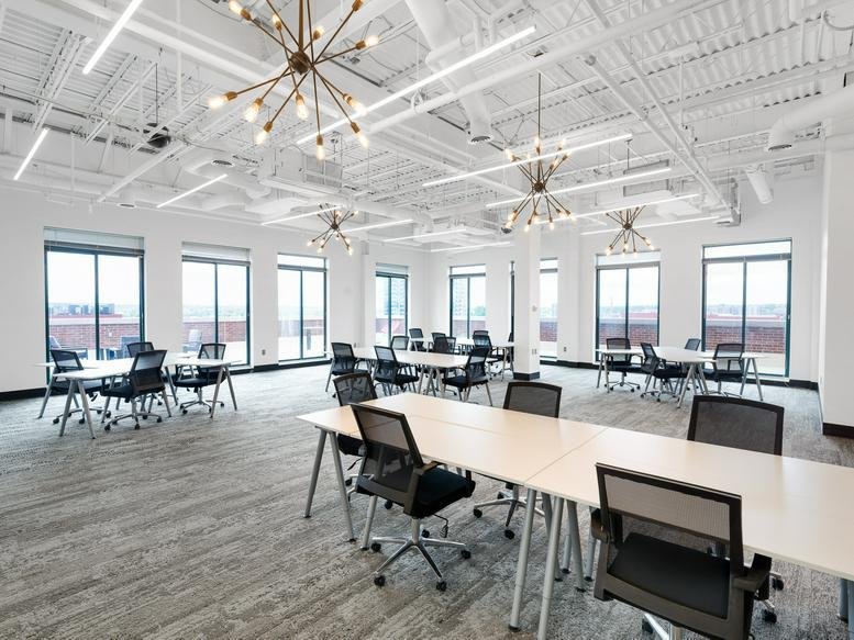 Spacious open-plan workspace at 11 S 12th Street featuring white desks and industrial ceilings.