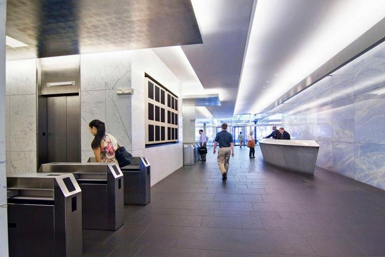 Bright lobby with marble walls, security turnstiles, and a sleek reception desk.