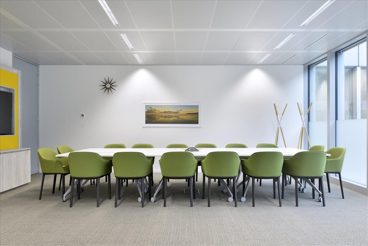 Spacious boardroom at Maple Street Offices, Springfield featuring green armchairs and a long white table.