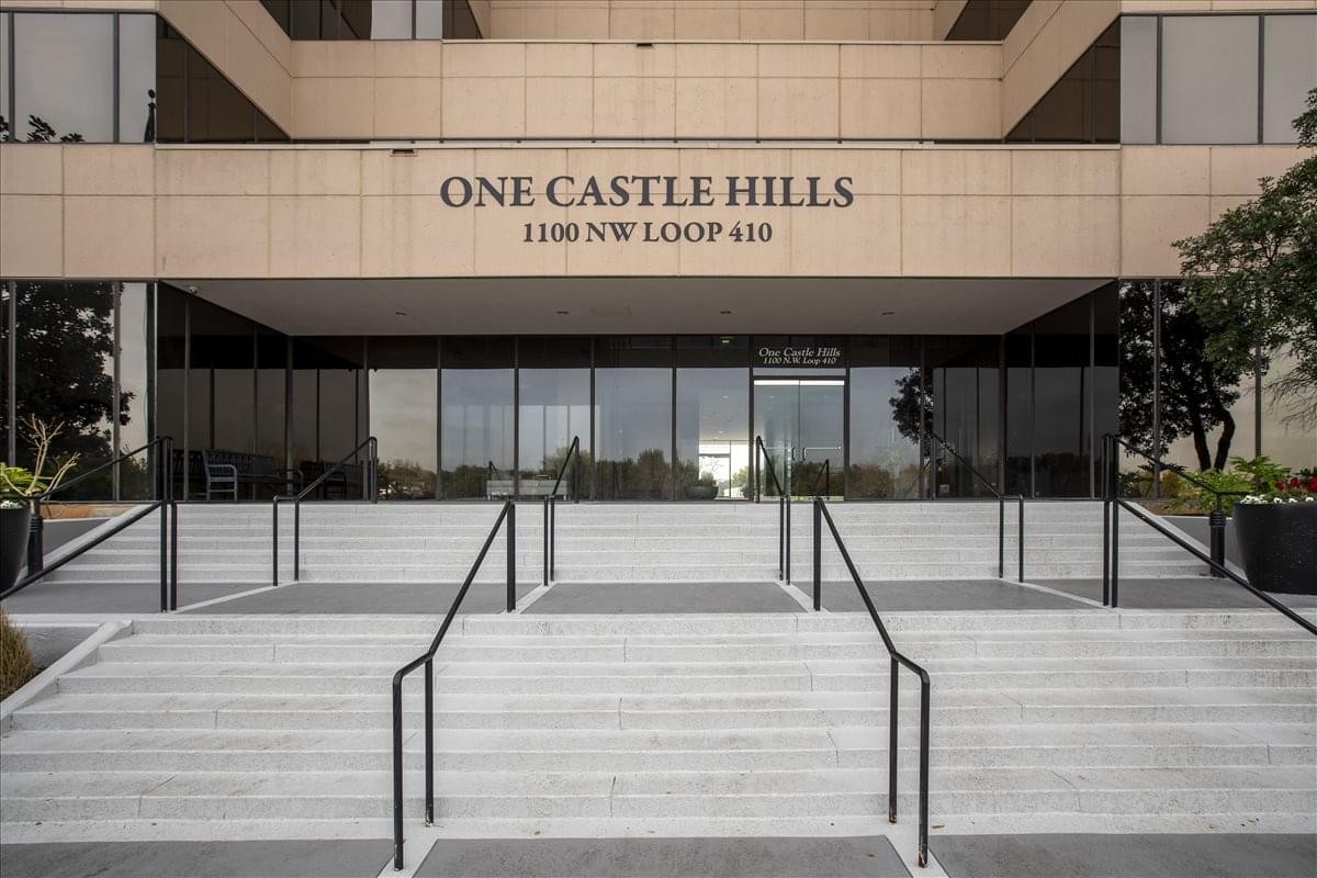 Exterior entrance of One Castle Hills with stone steps and glass doors.