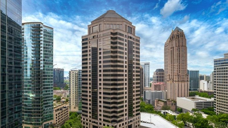 Exterior view of the multi-tiered 1100 Peachtree Street building against a blue sky.