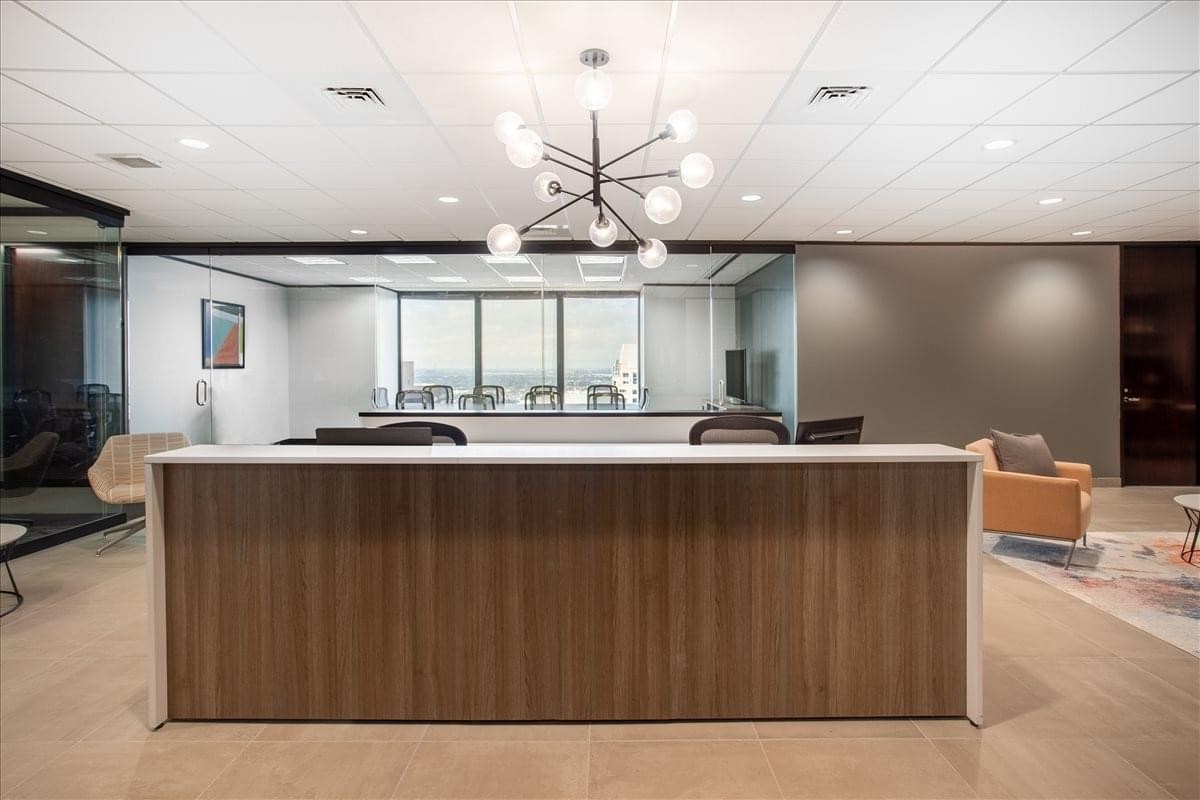 Reception area at Energy Centre Building, Suite 2900, featuring a wood-fronted desk and modern chandelier.