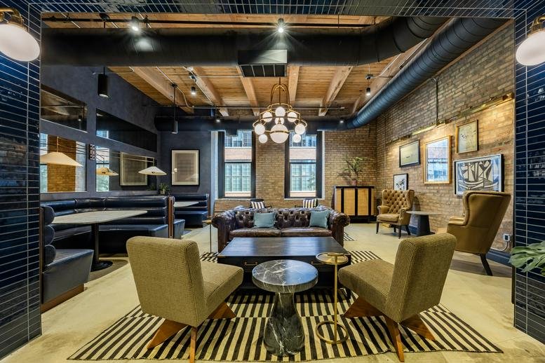 Spacious communal lounge at 1101 West Lake Street with plush seating, brick walls, and industrial ceilings.