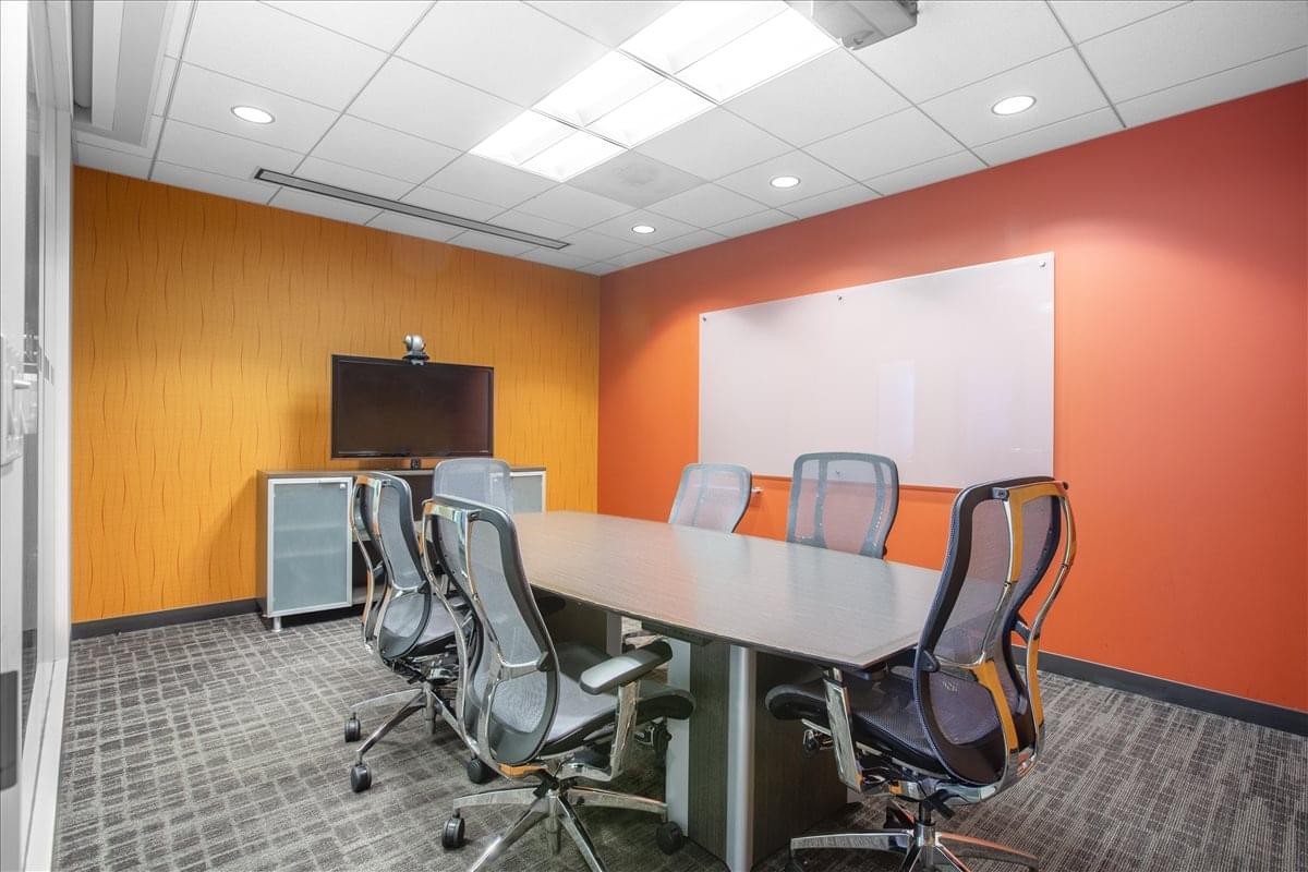 Meeting room at 111 West Ocean Blvd with orange feature walls and a large conference table.