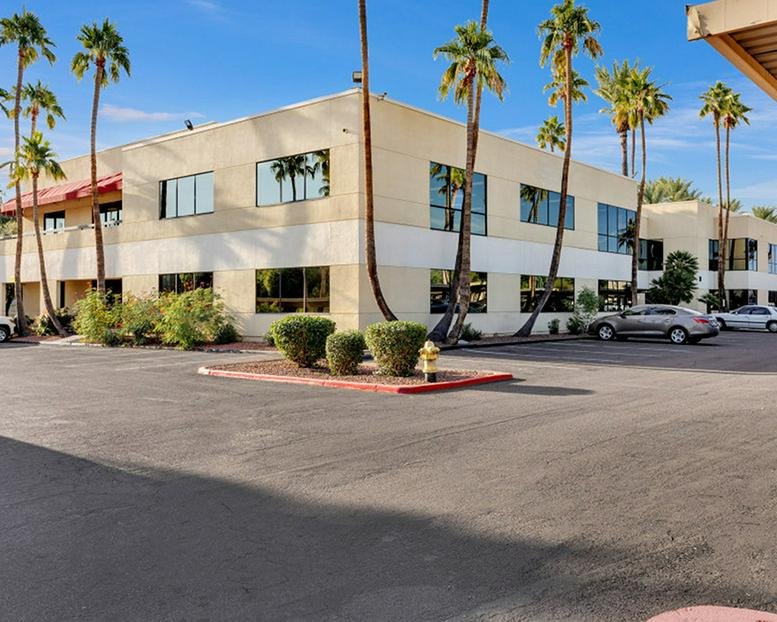 Exterior view of the light-colored office building at 11225 North 28th Drive with palm trees and parking.