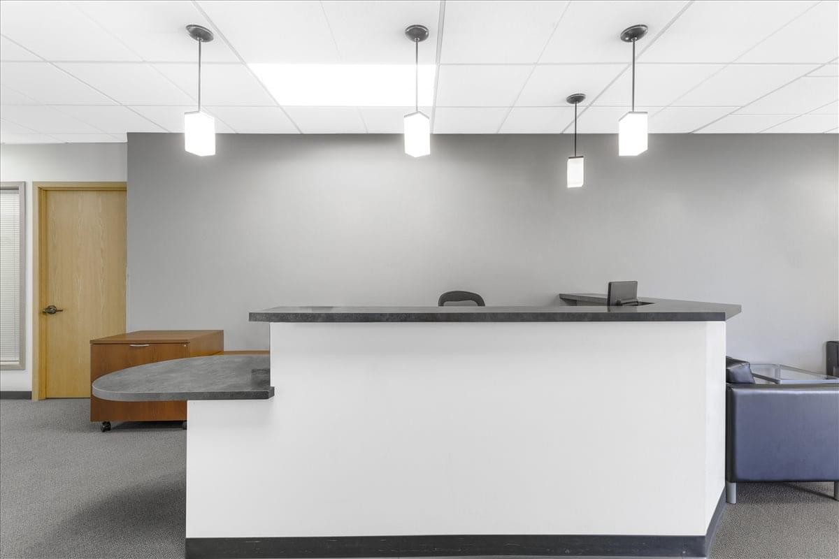 Minimalist reception area at 11335 NE 122nd Way, Suite 105, featuring a white desk and pendant lights.
