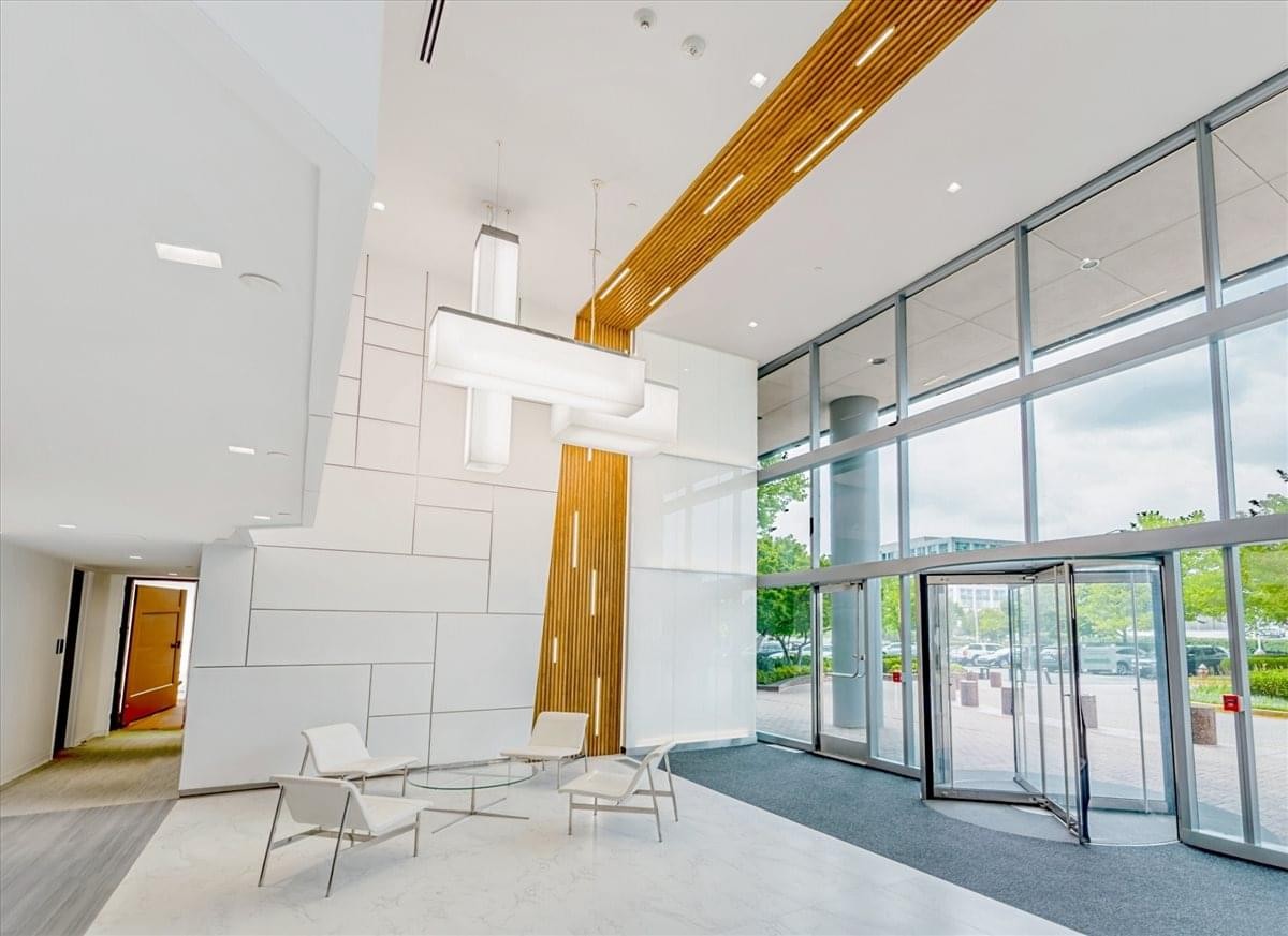 Spacious sunlit lobby with high ceilings, large windows, and contemporary white seating.