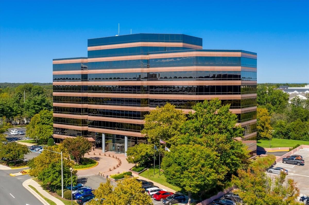 Wide exterior shot of the modern office building surrounded by greenery.