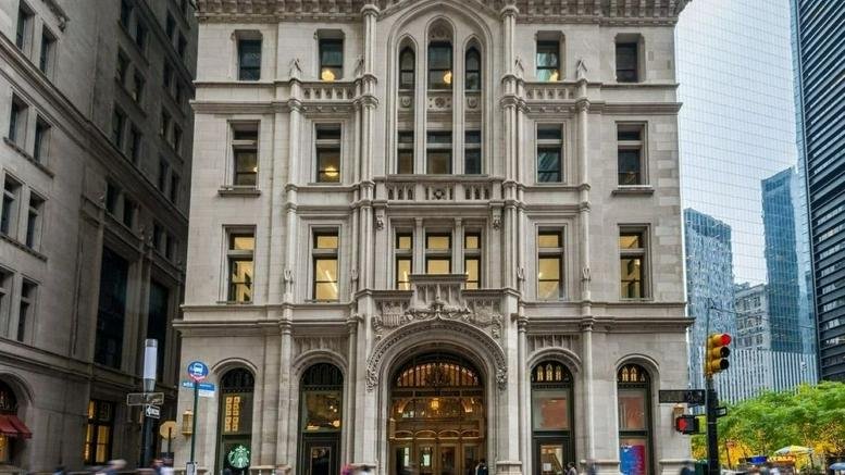 Grand historic stone exterior of 115 Broadway with arched windows and an ornate entryway.