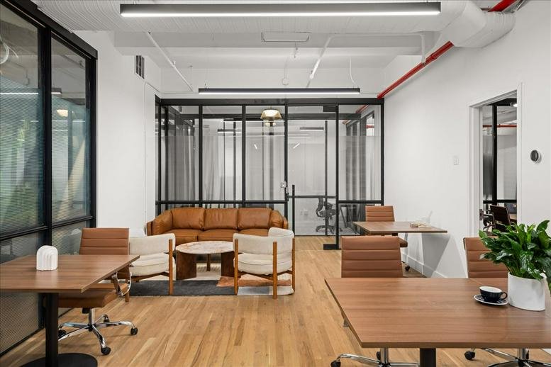 Spacious communal lounge at 115 East 23rd Street, 4th & 5th Floors, featuring a tan leather sofa and wooden desks.