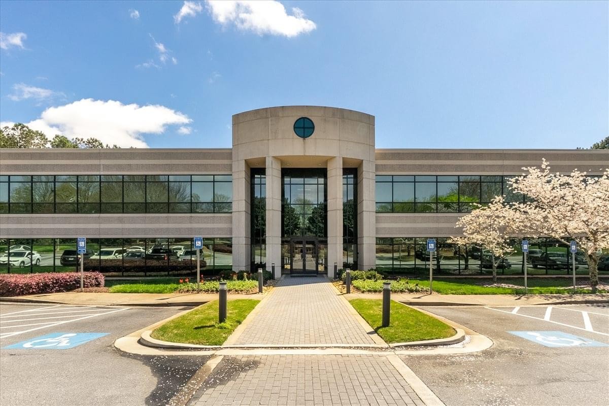 Exterior view of the arched stone entrance and glass facade at 11555 Medlock Bridge Road.
