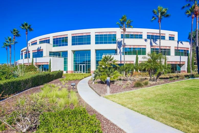 Exterior view of the curved facade and palm trees at 11622 El Camino Real, Suite 100.