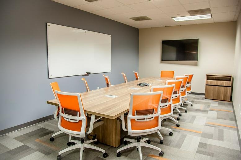 Professional meeting room at 11720 Amber Park Dr, Ste. 160, Alpharetta (Georgia) with orange chairs and a whiteboard.