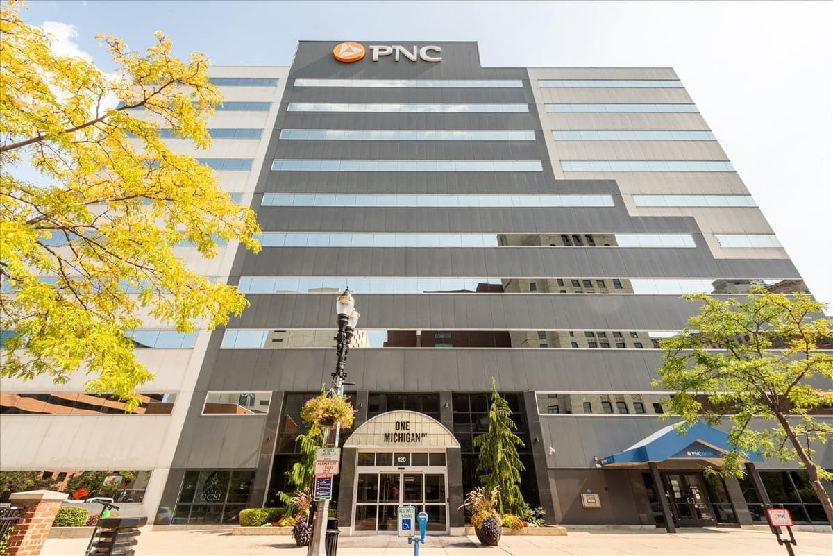 Facade of the One Michigan Avenue Business Center building with a large PNC sign and surrounding trees.