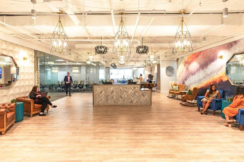 Spacious reception lobby at 1200 North Federal Highway with warm wood floors and ornate chandeliers.