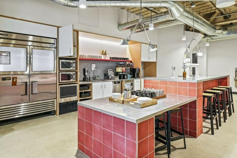 Spacious communal kitchen area featuring red tiled islands and professional stainless steel appliances.
