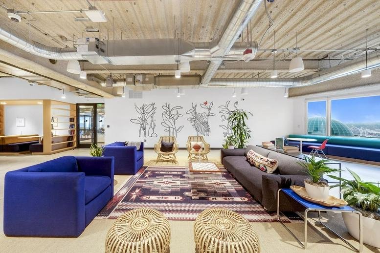 Colorful lounge area with blue velvet sofas, a patterned rug, and wall art.