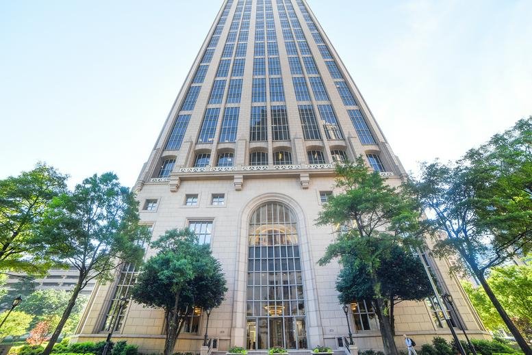 Street-level view of the building's grand arched stone entrance with surrounding greenery.