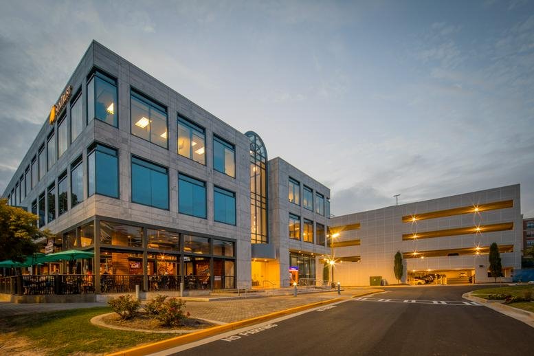 Exterior view of the multi-story modern stone and glass building at 121 Perimeter Center West.