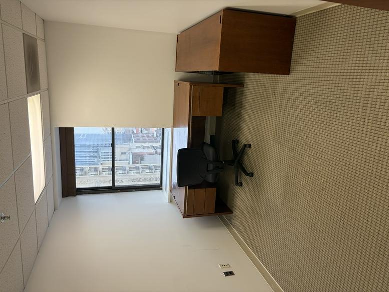 Private office with a wood desk and city view from a large window.