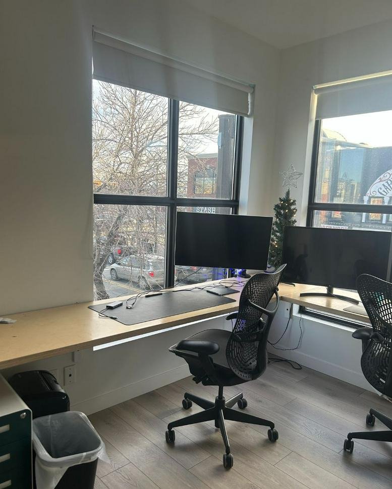 Sunlit coworking space at VennYYC Coworking Space, Inglewood, Calgary featuring wood desks and ergonomic chairs.
