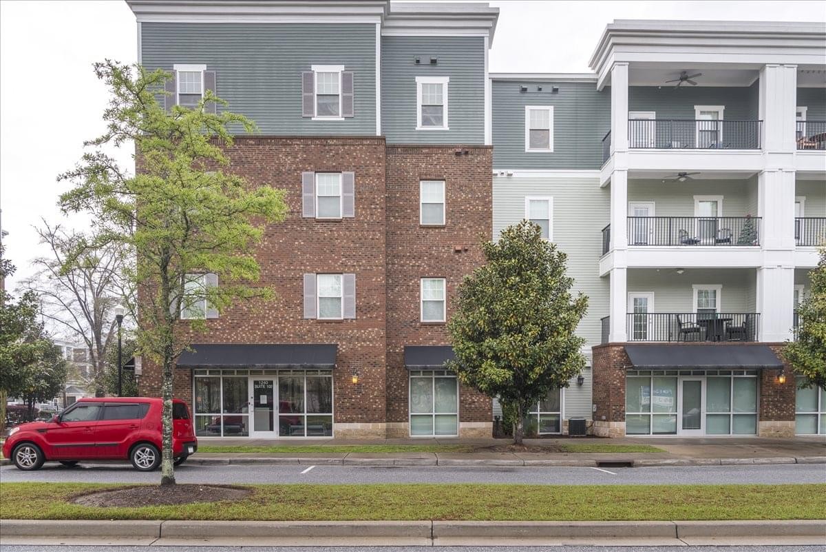 Exterior facade of Gregorie Ferry Landing Business Center with red car and green trees.