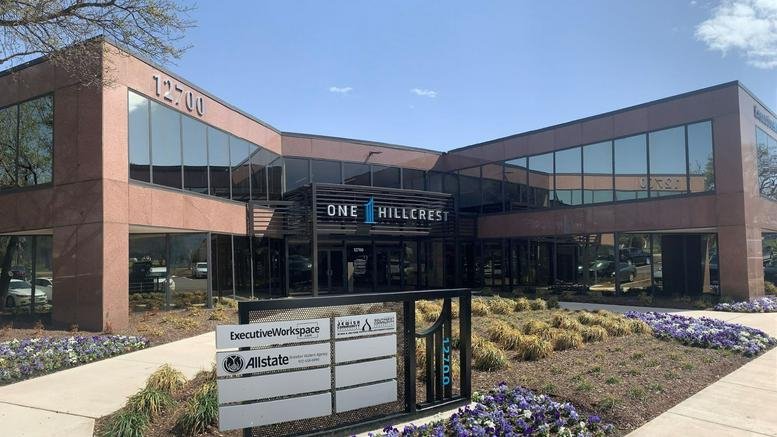 Main entrance of One Hillcrest showing the brick facade and landscaped flower beds.