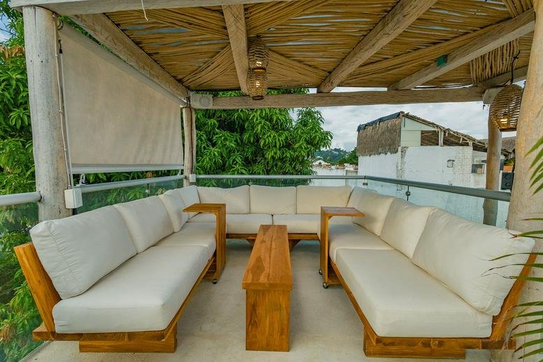 Rooftop lounge at Alchemize House with a wooden pergola and white sectional seating.