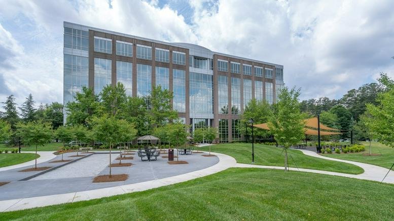 Exterior view of the brick and glass Deerfield Corporate Centre One with green lawn and trees.