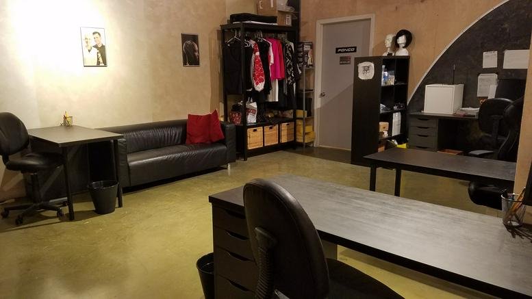 Open-plan workspace at Fonco Studios featuring a dark leather sofa, desks, and clothing racks.
