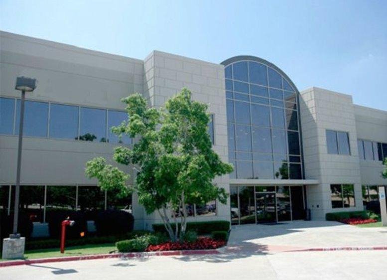 Exterior facade of 1333 McDermott Drive, Suite 200 with glass archway and manicured greenery.