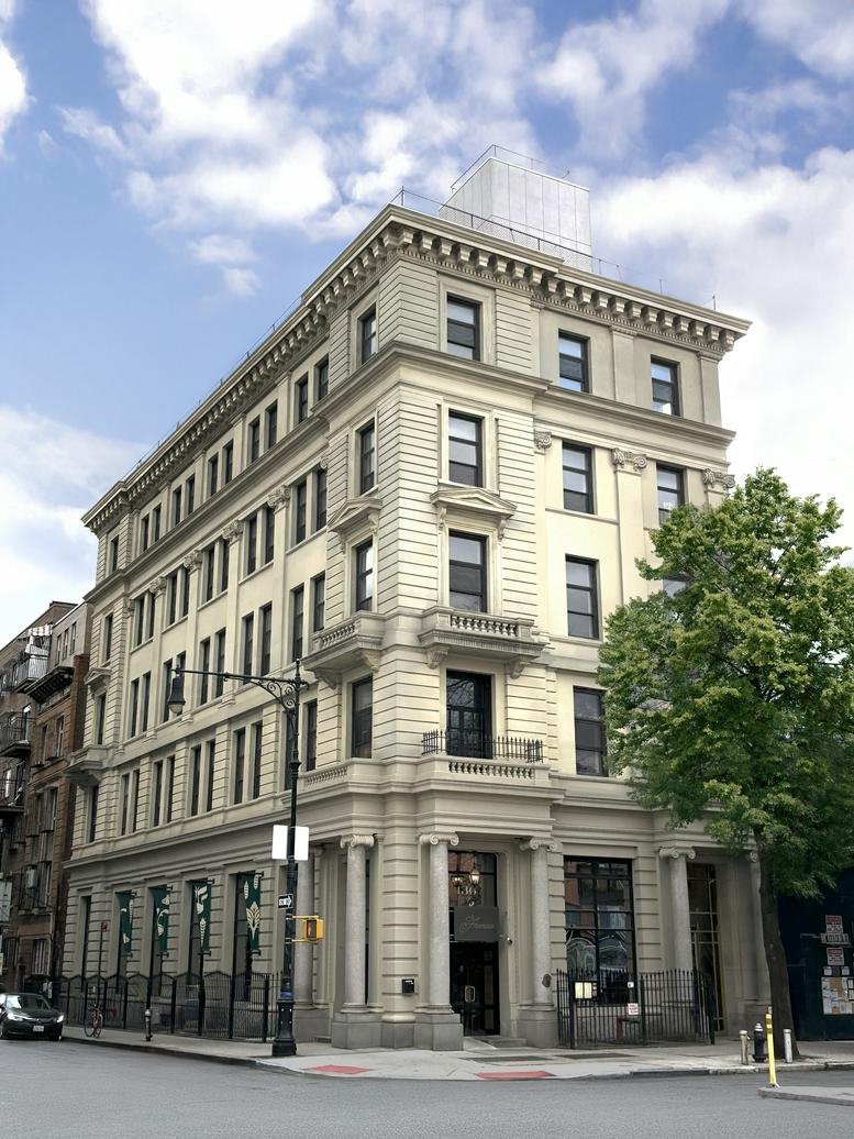 Five-story historic building with cream-colored stone details and large windows on a street corner.