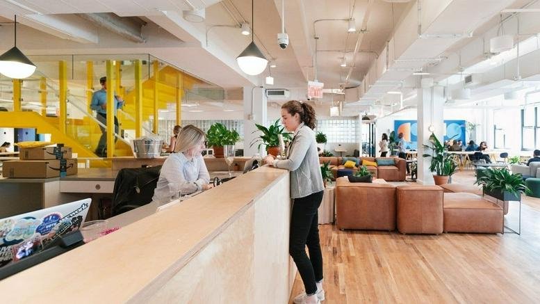Spacious reception area at 135 Madison Avenue featuring a warm wooden desk and yellow staircase.