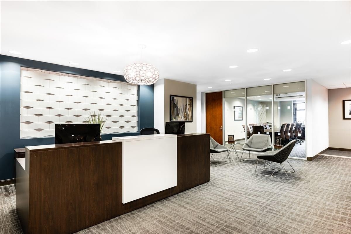 Bright reception area with a dark wood front desk and a comfortable glass-walled lounge.