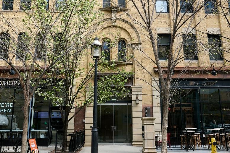 Exterior facade of the stone building at 140 Yonge Street with arched windows and tree-lined sidewalk.