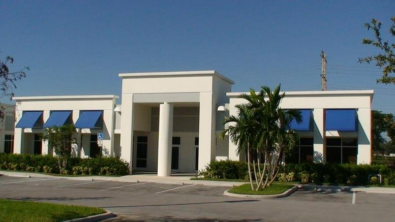Exterior view of the white building facade at 1401 Sawgrass Corporate Parkway with blue window awnings.