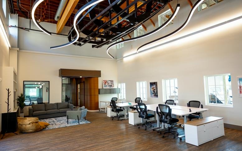Spacious communal lounge and coworking area at Clipper Coworks with unique wave-shaped lighting and wood ceilings.