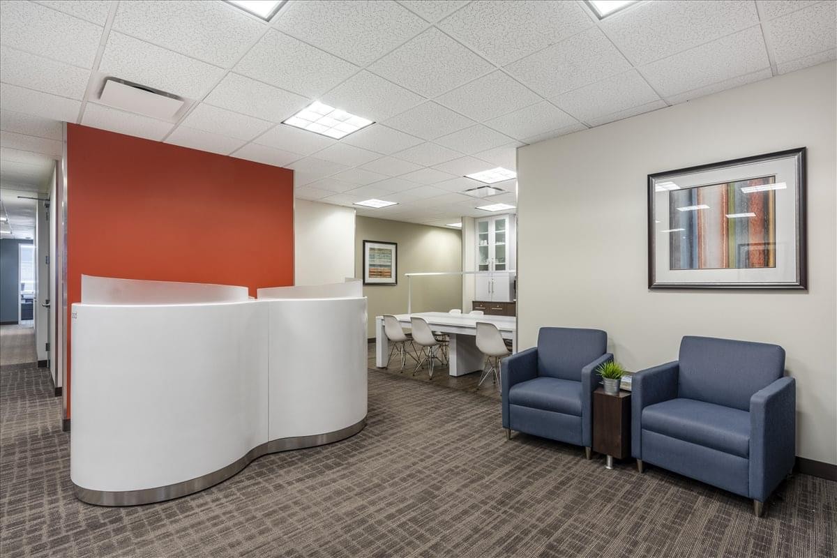 Waiting area at 1431 Opus Place, Suite 110, featuring blue armchairs and a curved white reception desk.