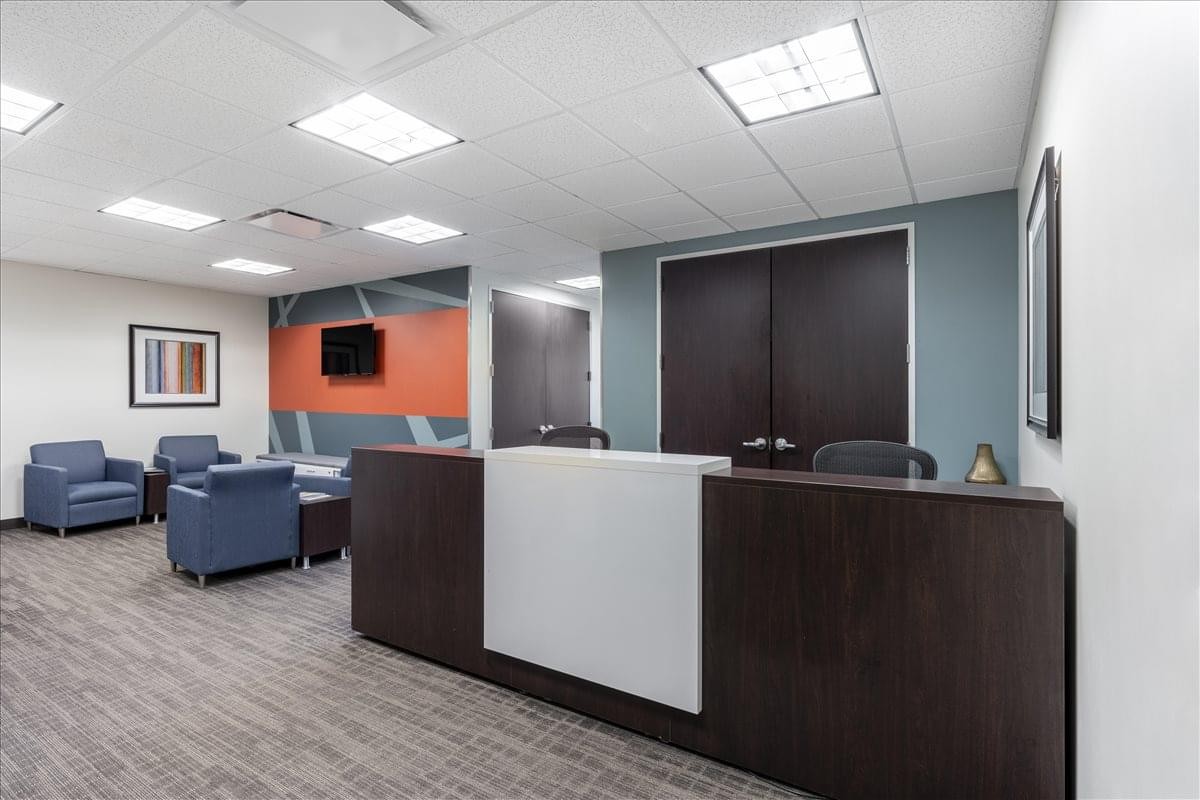 Spacious reception area at 1431 Opus Place, Suite 110 with dark wood desk and blue seating area.