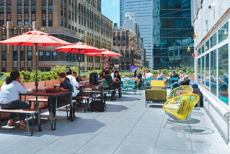 Rooftop terrace at 1460 Broadway, Times Square with red umbrellas, tables, and city views.