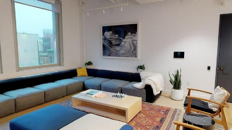 Bright breakout lounge at 148 Lafayette Street featuring a large modular sofa and colorful area rug.