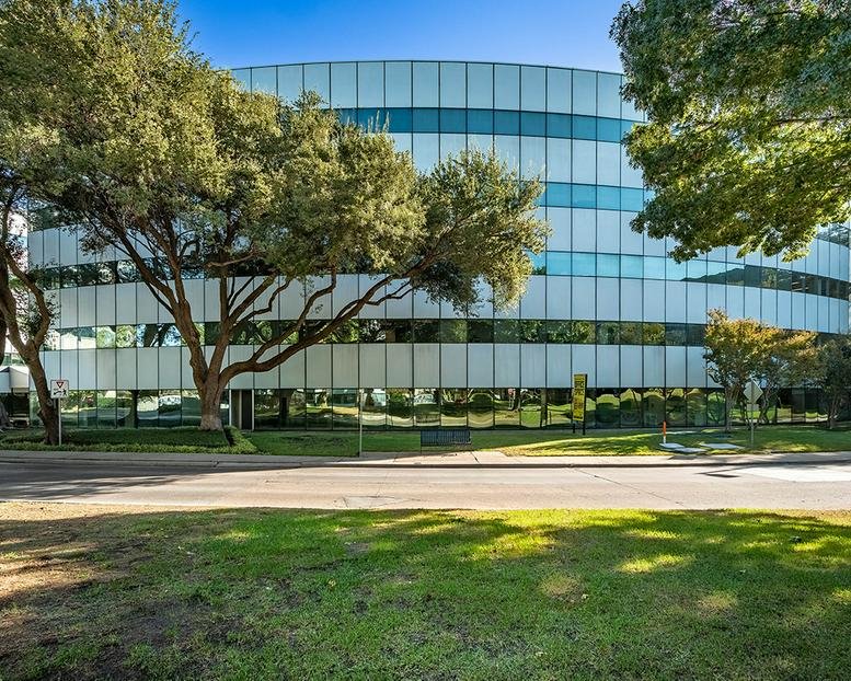 Exterior view of the curved glass facade and green landscaping at 14800 Quorum Drive.
